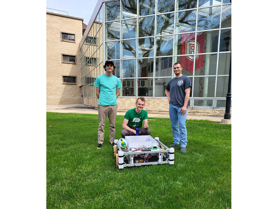 Bradley students posing in front of lawn care robot.