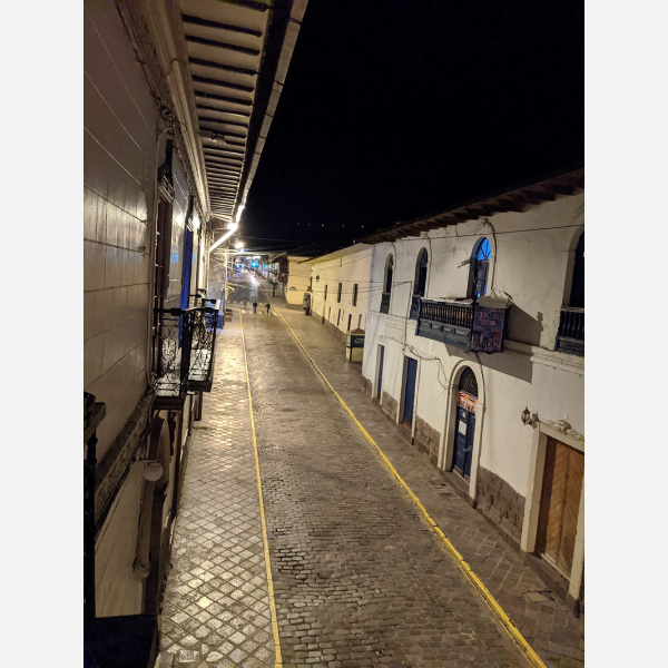 A nighttime view of a street in Cusco, Peru, with just two solitary pedestrians out before the 8 p.m. curfew.