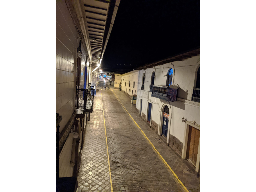 A nighttime view of a street in Cusco, Peru, with just two solitary pedestrians out before the 8 p.m. curfew.